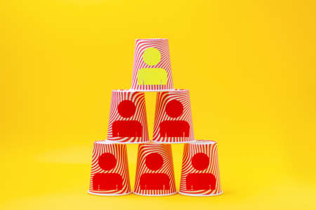 Pyramid of paper cups with the image of the symbols of the little man. Yellow background. The concept of business management, development and career.の写真素材