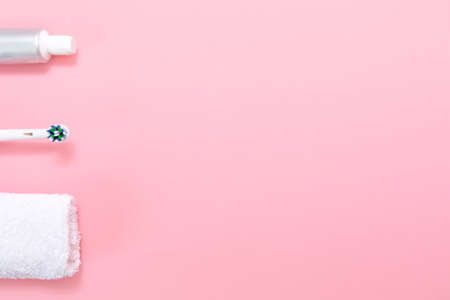 Electric toothbrush, towel, and toothpaste. Flat lay. Pink background. Copy space. Concept of oral hygiene.の写真素材