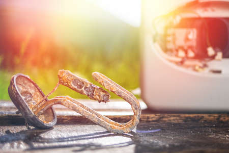 The water heating element damaged from corrosion lies on a wooden table next to the boiler. In the background green grass in the yard. Close up. Light.の写真素材