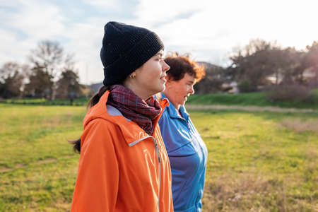 Granddaughter walking down the park with her older grandmother. Family outdoor vacation. Side view. International Day of Older Persons.の写真素材