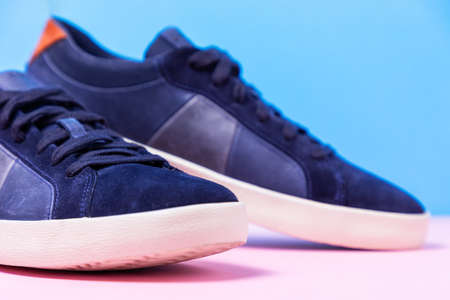 Man's new sneakers toes made of blue leather laid out on a pink-blue background. Close up.の写真素材