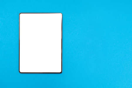 White digital tablet on blue background. Flat lay. Mock up. Copy space. The concept of digital devices and the Internet.の写真素材