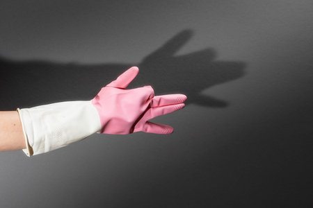 Shadow theater. Hands in rubber gloves shows the figure of a dog. On the dark wall is a shadow of...