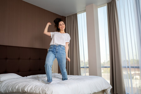 Positive emotions. Happy young woman dancing in the room. Bottom view. Windows on the background. Inside.の写真素材