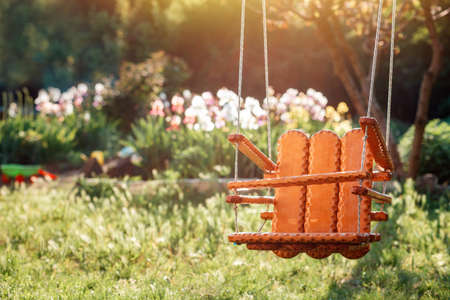 International Children's Day. Handmade wooden swing hanging in the kindergarten, on the summer sunny playground. Nobody. Family planning concept.の写真素材