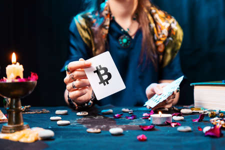 The fortune teller shows a card with the bitcoin currency. The concept of unpredictable cryptocurrency exchange trading.の写真素材