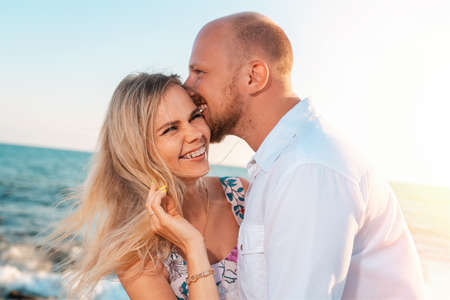 A couple of happy young men and women hug and kiss. In the background, the ocean and the sky. Vacation romance conceptの写真素材