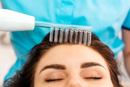 Hair care. Woman receives a procedure using the darsonval device. Close-up of the head. Concept of...