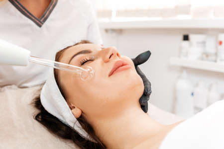 Darsonval cosmetology apparatus. Professional skin care in the salon. Woman on the darsonval therapy in beauty salon. Close up.の写真素材
