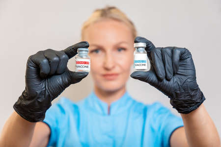 Covid-19 vaccination. A doctor in medical gloves holds two ampoules with a vaccine against...