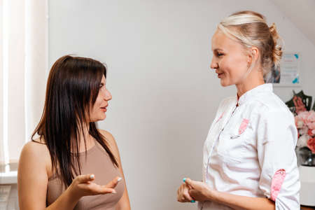 Consultation with specialist. A young woman at a reception with a professional bautician in a beauty salon. Concept of cosmetology and aesthetic medicine.の写真素材
