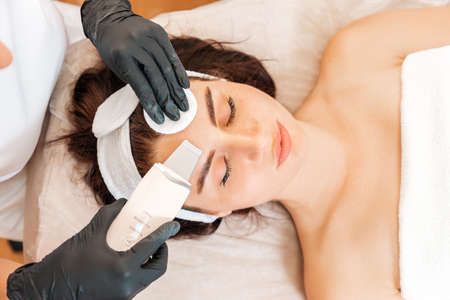Cleaning procedure at the beauty salon. Cosmetologist cleans the client's forehead using a...