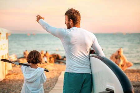 Father and daughter are walking along the beach, looking for a place to swim and surf in the sea....
