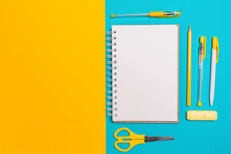 Composition of copybook, office supplies on blue and yellow background. Flat lay. Copy space. Concept of back to school.の写真素材