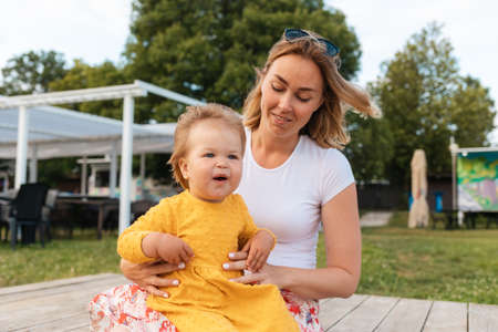 Summertime. Portrait of a mother and her baby girl sitting relaxed at the park. The concept of...