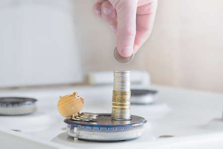 the concept of economy and investment .a man's hand puts a coin on a stack of money on the...