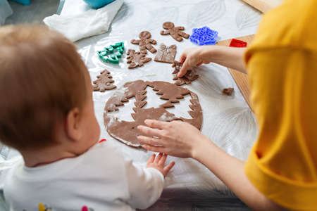 Mother and baby together cut out cookies from the dough. Top view from the shoulder. Christmas concept and family cooking meals with children.の写真素材