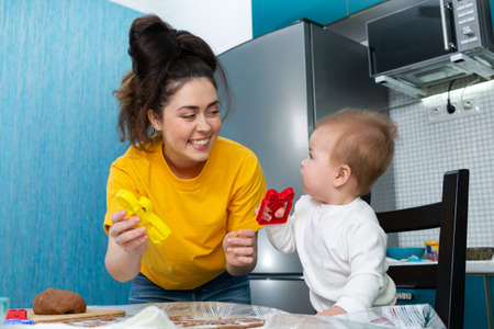 Portraits of happy mother and baby play with cookie cutters while cooking. The concept of mother's Day and homemade meal with the children.の写真素材