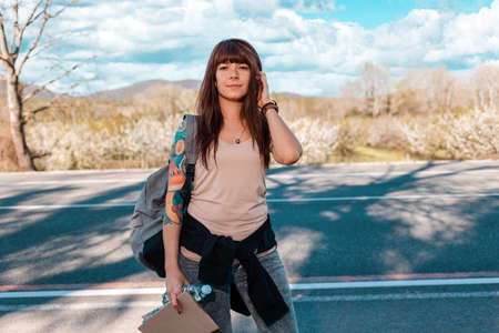 Smiling caucasian young woman with tattoed hand holding a cardboard sign. Outdoor. The concept of...