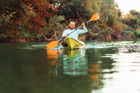 Kayaking on the river. Adult caucasian bearded man floating at the kayak. Copy space. The concept of the World Tourism Day.の写真素材