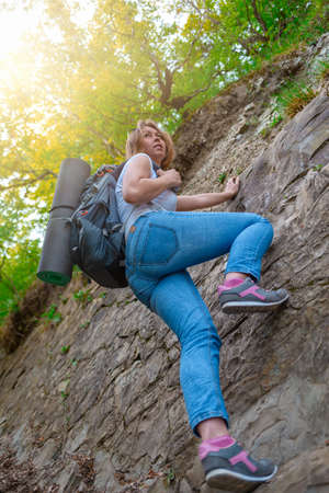 A young woman is engaged in rock climbing. Leisure and active sports. Light. Bottom view.の写真素材