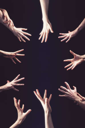 Many hands reach out to the center. Vertical orientation. Black background. Copy space. The concept of greed, psychology and social relations.の写真素材