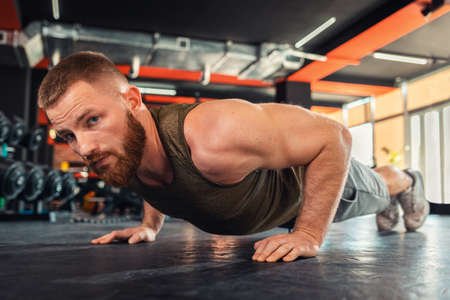 Portrait of young bearded athletic man doing push-ups in the gym. Close-up. The concept of fitness...