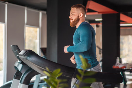 Portrait of a young bearded athletic man training on a treadmill. Copy space. Concept of sport and...