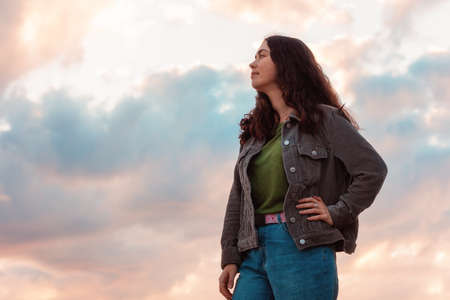 Portrait of a smiling young woman. In the background is a dramatic sunset. Copy space. The concept of psychology and mental health.の写真素材