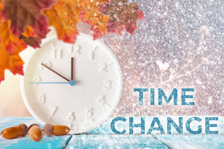 The concept of time change. Clocks and leaves on a wooden table with acorns.の写真素材