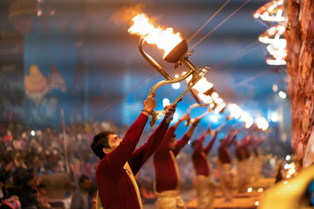 12/17/2019, Varanasi, India. Sacred religious ceremony Arati in the temple. Men standing in a row hold lighted torches. Night. Outdoors.のeditorial素材