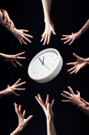 A crowd of people is drawn to the clock in the center. Hands close-up. Black background. Vertical. The concept of stress, greed and haste.の写真素材