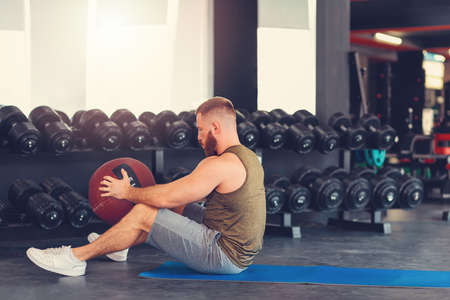 Bearded athletic man training in the gym with a sports ball. Side view. Copy space. The concept of fitness.の写真素材