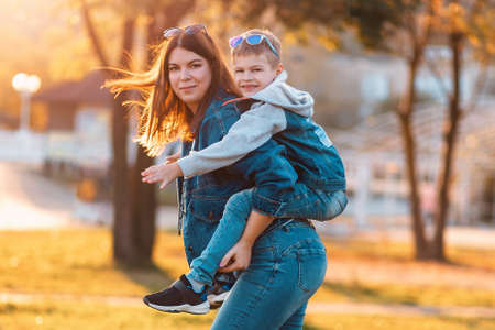 A smiling young mother and son play in an autumn park. The concept of a happy childhood.の写真素材