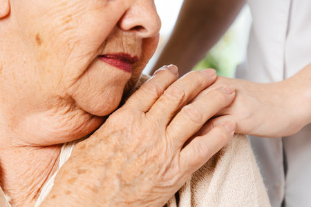 International Day of Older Persons. Old woman clasped nurses hand. Close-up. The concept of nursing home.の写真素材