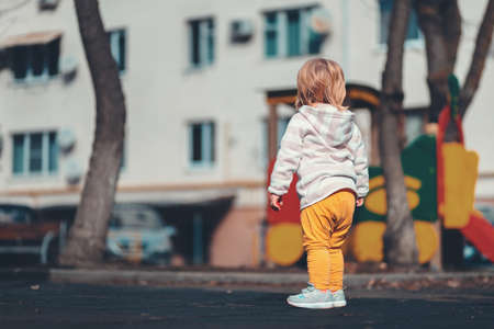 A lost child. A small baby is standing alone on the playground. The concept of adoption of children.