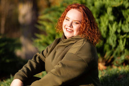 Portrait of a young happy overweight woman posing at he park. The concept of psychology.の写真素材