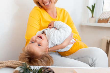 Portrait of happy young mother is playing and having fun with her little child. Concept of motherhood.の写真素材