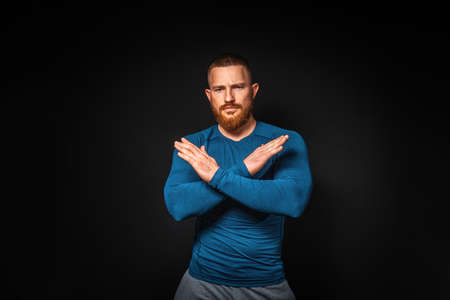 Athletic muscular man posing on a black background, crossed hands. Copy space. Concept of prohibition.の写真素材