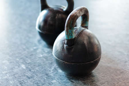 Two black cast iron weights on the floor. Sports equipment in the gym. Close up.の写真素材