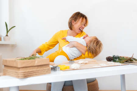 Smiling mother playing with her child sitting at a table with a dough and cookies. Christmas home leisure.の写真素材