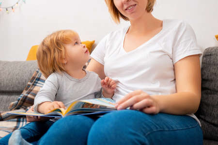 An inquisitive child looks at his mother, who is reading a book. The concept of child development.の写真素材