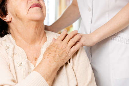 International Day of Older Persons. Nurse put her hand on the shoulder of a senior woman. Close-up. The concept of nursing home.の写真素材