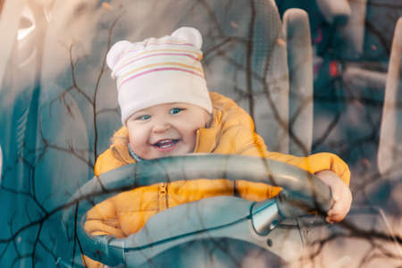 Portrait of little happy child is sitting at the wheel of a car. View through the windshield of the car. Driving training concept.の写真素材