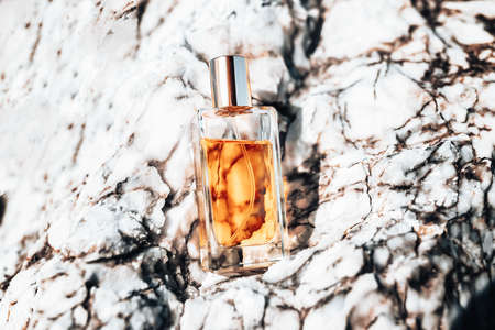 Perfumery. A glass transparent bottle of golden perfume standing on a white marble stone. Top view.の写真素材