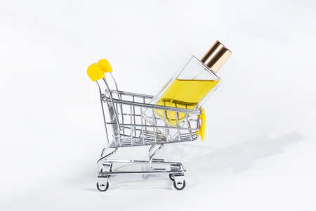 Golden transparent perfume bottle in pushcart on white background. Shopping and sale concept.の写真素材