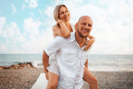 Valentines day. Funny couple of young caucasians man and woman. In the background blue cloudy sky and sea. Vacation romance concept.の写真素材