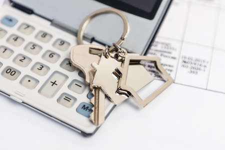 Close-up keys with a metal keychain house are on the calculator. Mortgage and loan termination.の写真素材