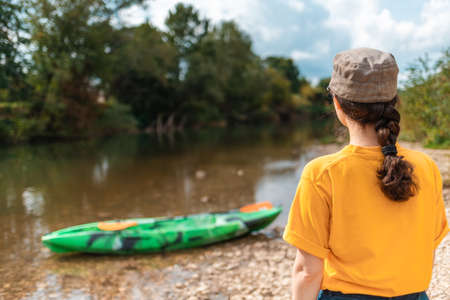 A young woman looks at a kayak. rear view. copyspace. The concept of kayaking and outdoor activities.の写真素材