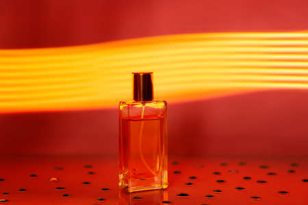 Transparent glass rectangular bottle of perfume on golden neon background. Fashion style perfumery template. copy spaceの写真素材